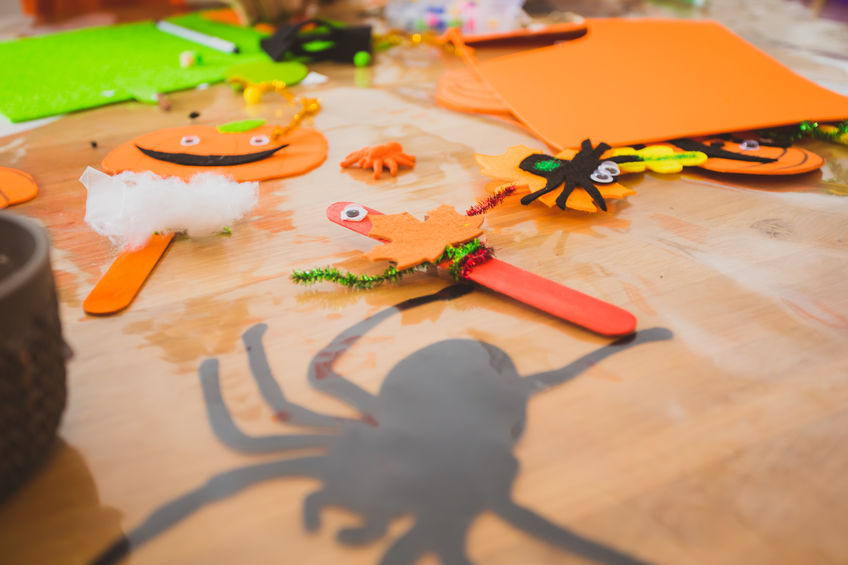 Above view many different Halloween pumpkins made of felt or paper placed on wooden surface. Handmade halloween style bookmarks.