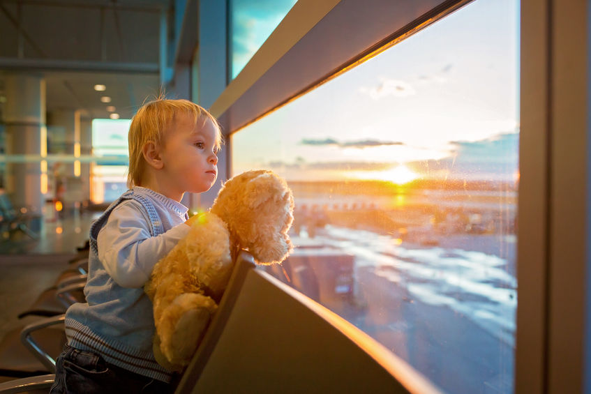 Children, traveling with stuffed bear, waiting at the airport to board the aircraft